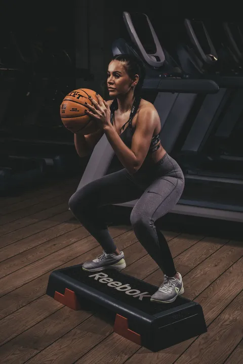 Step squats with a Basket Bullet medicine ball